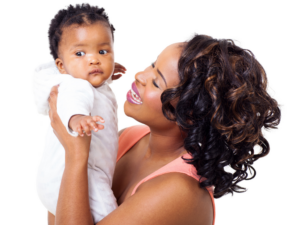 A person holds a baby wearing a white onesie, looking at each other with smiles against a white background.