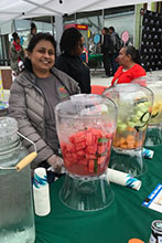 Picture of a person volunteering at a stand serving healthy drinks