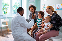 A photo of a family of four talking to a doctor in a pediatric doctor's office