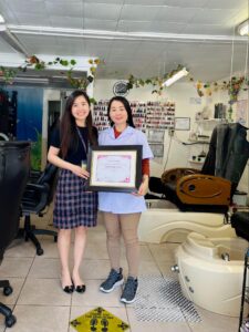 Photo of two workers at a nail salon holding a certificate