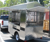 A towable compact food cart with side and rear panels that open