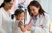 This image is of a child and her mother smiling as the female doctor holds the child's hand. 