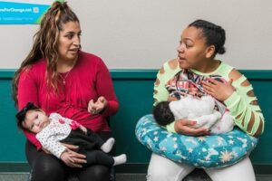 An image of two woman holding an infant each. 