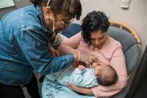 An image of two woman with one holding an infant.