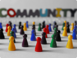 A collection of colorful pawns are scattered across a white surface, with the word "COMMUNITY" blurred in the background.