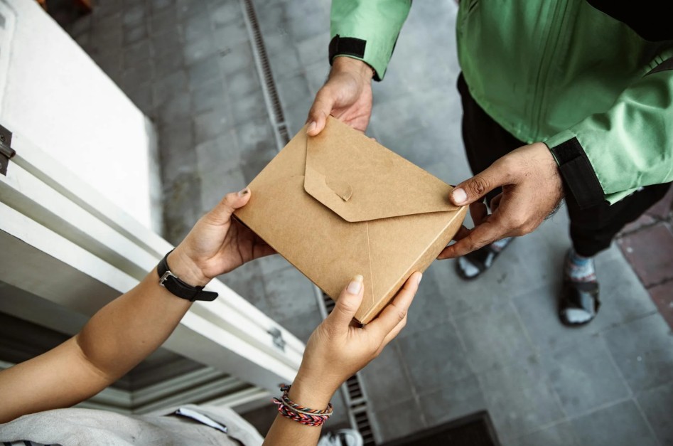Image of a delivery person handing off a food package to a customer.