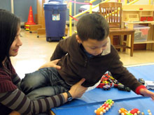 A woman holding a child while plays with toys. 